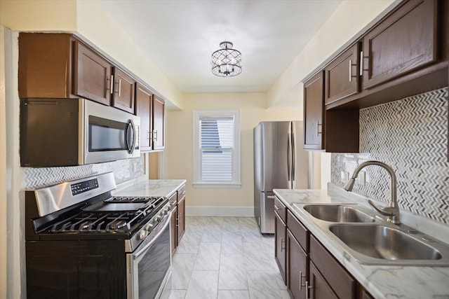 kitchen featuring stainless steel appliances, a sink, light marble finish flooring, decorative backsplash, and dark brown cabinetry