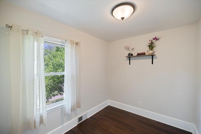 spare room with baseboards and dark wood finished floors