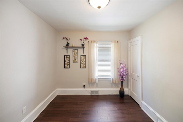 spare room with dark wood-type flooring and baseboards