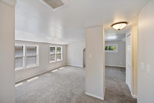 carpeted empty room featuring vaulted ceiling, plenty of natural light, baseboards, and arched walkways