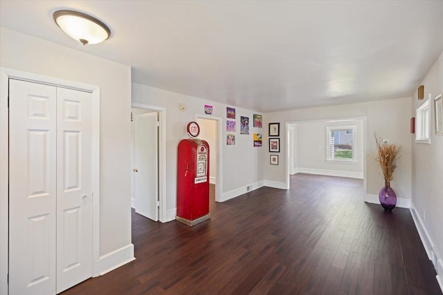 unfurnished living room featuring dark wood finished floors and baseboards