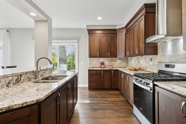 21212 Old Lake George Blvd NW, Oak Grove, MN 55303 - kitchen with stainless steel gas range oven, wall chimney range hood, a sink, light stone counters, and dark wood-type flooring