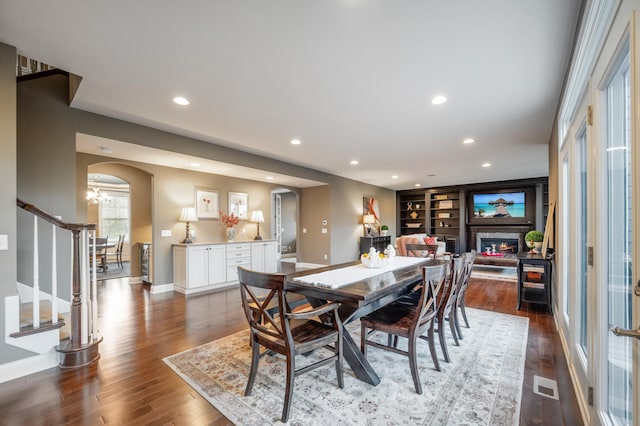 16302 Sohm Ct, Eden Prairie, MN 55347 - dining room featuring visible vents, recessed lighting, dark wood-style flooring, arched walkways, and a glass covered fireplace
