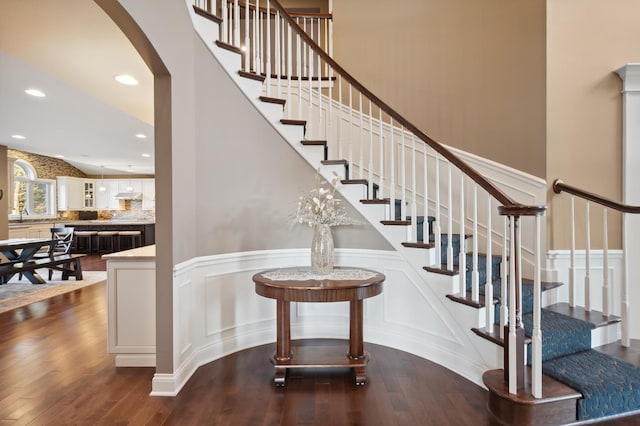 16302 Sohm Ct, Eden Prairie, MN 55347 - stairway featuring wainscoting, hardwood / wood-style flooring, arched walkways, and recessed lighting