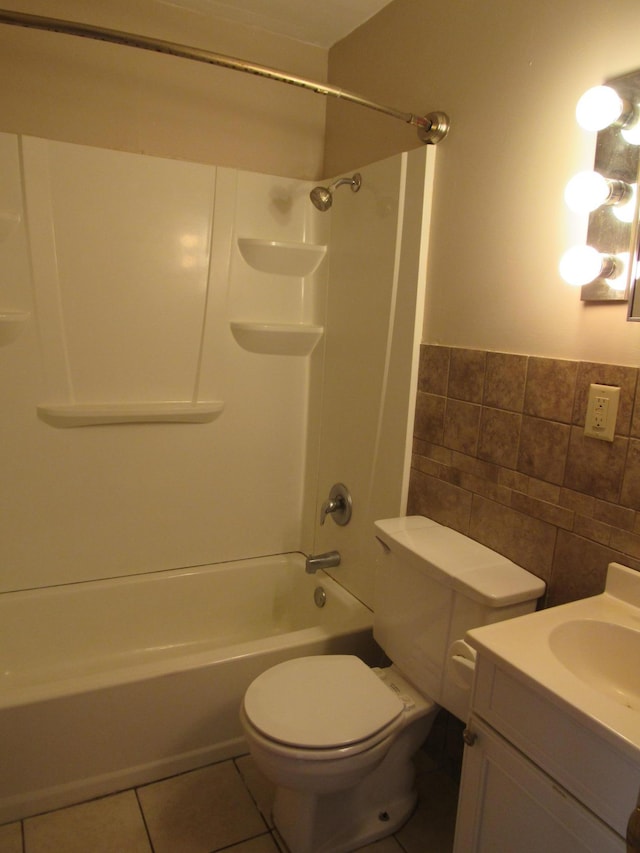bathroom with tile patterned floors, tile walls, toilet,  shower combination, and vanity