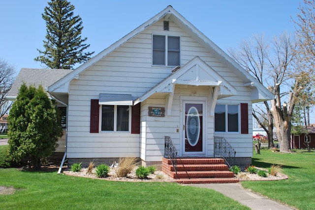 bungalow-style house with a front lawn and entry steps
