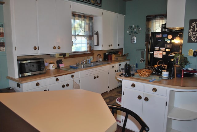 kitchen with stainless steel microwave, freestanding refrigerator, and white cabinets