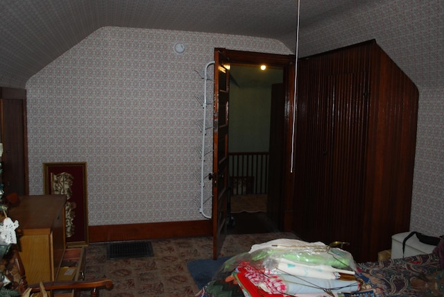 bonus room featuring lofted ceiling, wallpapered walls, and baseboards