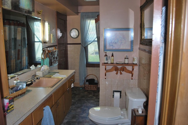 bathroom with tile walls, toilet, vanity, and wainscoting