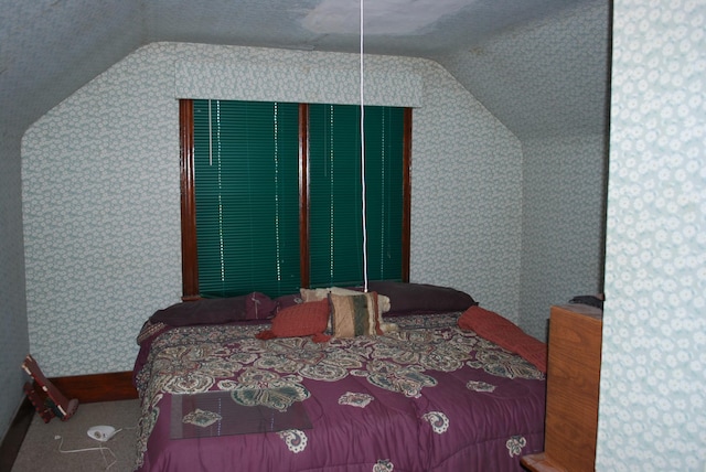 carpeted bedroom with wallpapered walls and vaulted ceiling