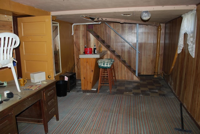 finished basement featuring wood walls, stairs, and dark colored carpet