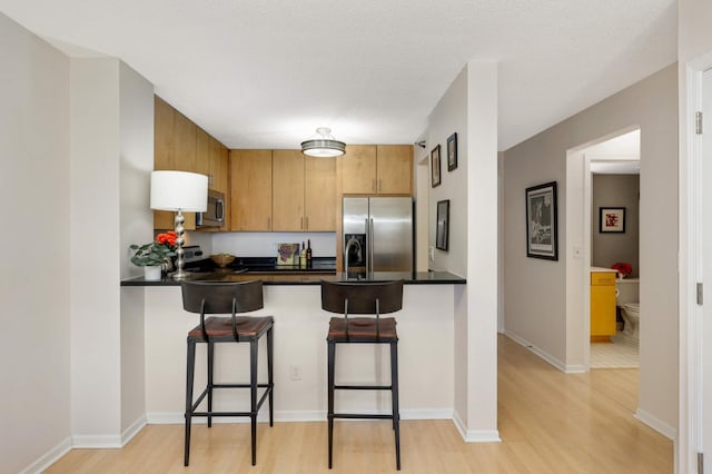 401 1st St Unit 1321, Minneapolis, MN 55401 - kitchen with appliances with stainless steel finishes, a peninsula, light wood-style flooring, and dark countertops