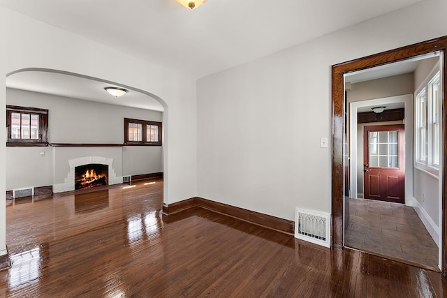 864 Fuller Ave, Saint Paul, MN 55104 - unfurnished living room featuring wood finished floors, arched walkways, and a fireplace
