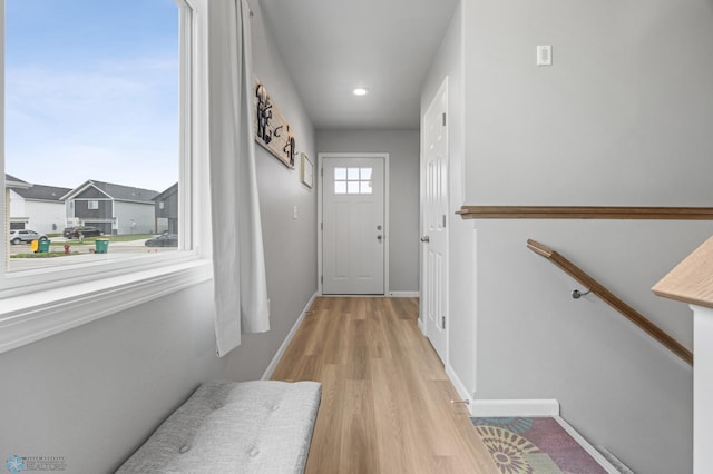 doorway featuring light wood finished floors, baseboards, and recessed lighting