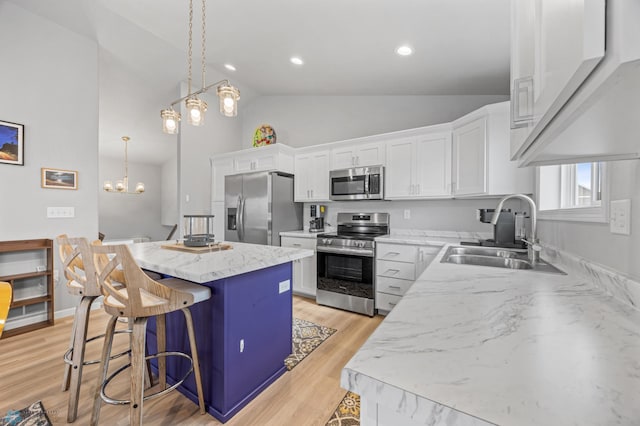 kitchen with stainless steel appliances, a sink, a center island, white cabinetry, and a breakfast bar area