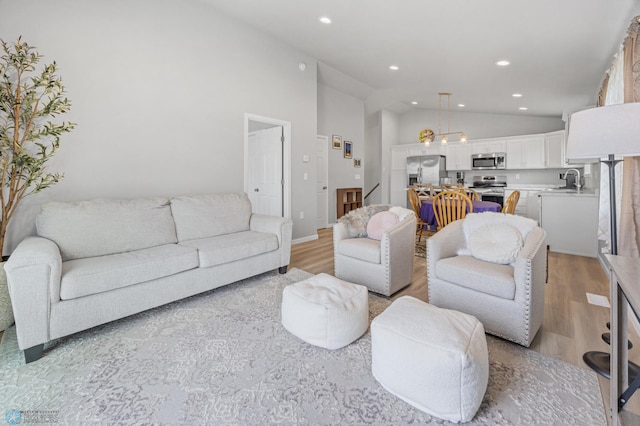 living area featuring lofted ceiling, recessed lighting, light wood-style flooring, and baseboards