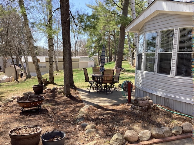 view of green lawn featuring an outdoor fire pit, a patio area, and outdoor dining space