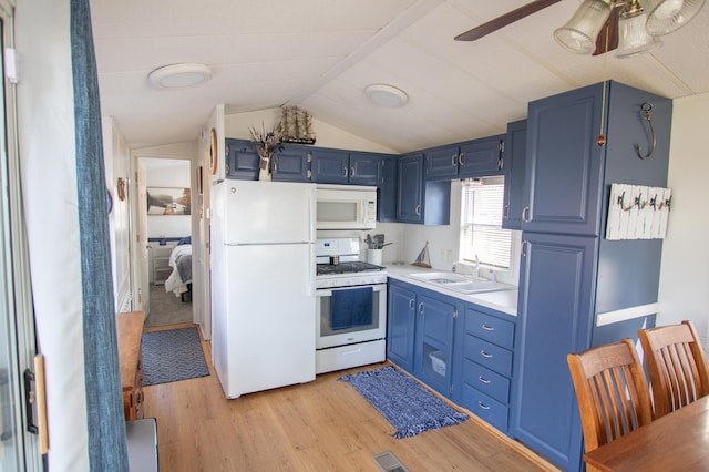 kitchen featuring white appliances, blue cabinets, light wood-style floors, a sink, and vaulted ceiling