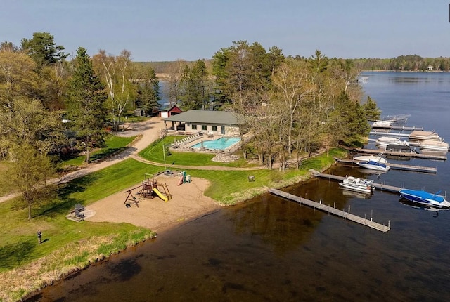 bird's eye view of a nearby body of water, a pool area, and a heavily wooded area
