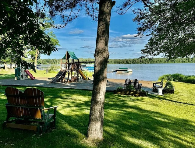 view of grassy yard featuring a playground and a water view