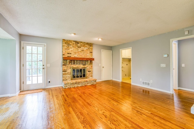 1900 Vernon Dr S, Minnetonka, MN 55305 - unfurnished living room featuring light wood finished floors, a textured ceiling, a brick fireplace, and baseboards