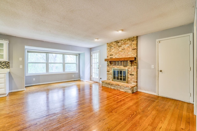 1900 Vernon Dr S, Minnetonka, MN 55305 - unfurnished living room with light wood-style flooring, a textured ceiling, a fireplace, and baseboards