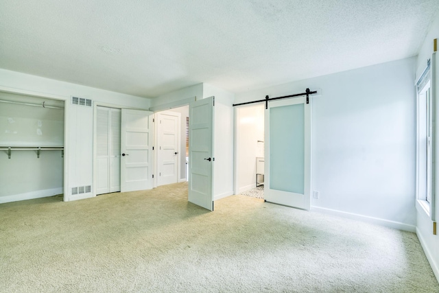 1900 Vernon Dr S, Minnetonka, MN 55305 - unfurnished bedroom featuring multiple closets, carpet flooring, a barn door, a textured ceiling, and baseboards
