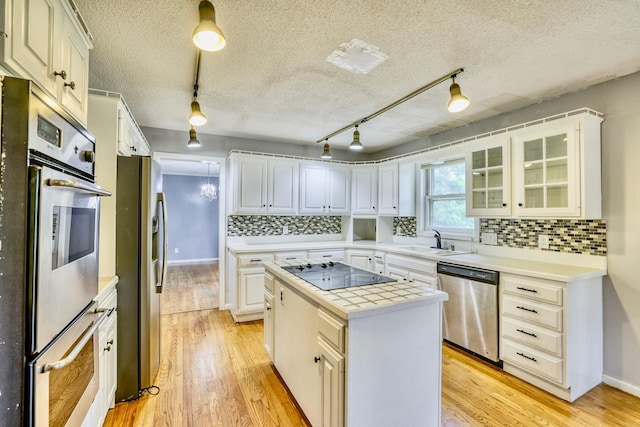 1900 Vernon Dr S, Minnetonka, MN 55305 - kitchen with appliances with stainless steel finishes, a sink, a kitchen island, light wood-style flooring, and backsplash