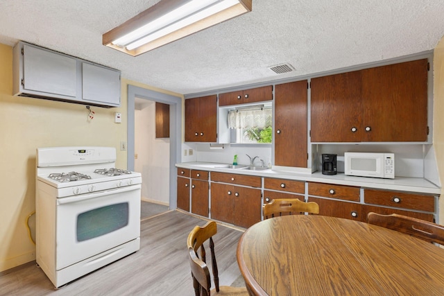 100 2nd St S, Delano, MN 55328 - kitchen featuring white appliances, a sink, a textured ceiling, light wood finished floors, and light countertops