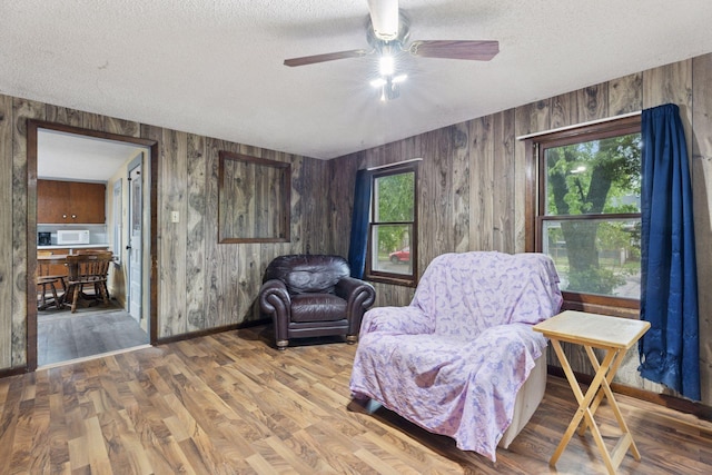 100 2nd St S, Delano, MN 55328 - living area with a textured ceiling, wooden walls, a ceiling fan, wood finished floors, and baseboards