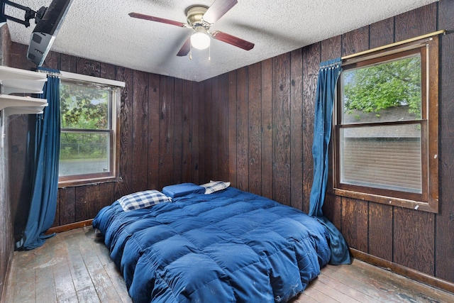 100 2nd St S, Delano, MN 55328 - bedroom featuring wood-type flooring, a textured ceiling, wooden walls, and a ceiling fan