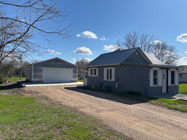 view of side of home with a garage, central AC, metal roof, an outdoor structure, and a standing seam roof