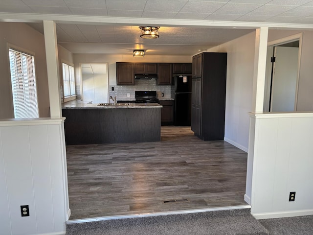 kitchen featuring freestanding refrigerator, range with electric cooktop, under cabinet range hood, dark brown cabinetry, and a peninsula