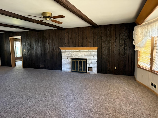 314 Burr Oak Dr, Albert Lea, MN 56007 - unfurnished living room featuring beamed ceiling, wood walls, carpet, ceiling fan, and a stone fireplace