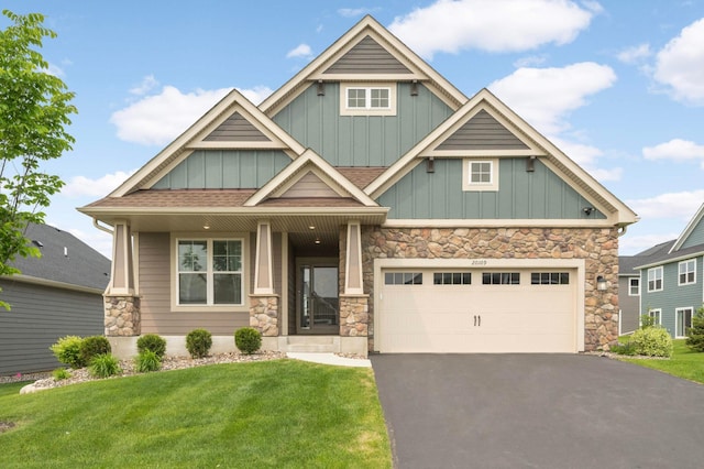20109 Geneva Trl, Lakeville, MN 55044 - craftsman-style house featuring board and batten siding, asphalt driveway, stone siding, a front yard, and covered porch