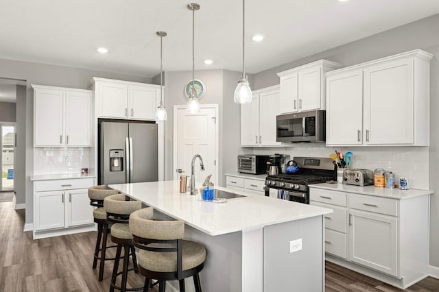 20109 Geneva Trl, Lakeville, MN 55044 - kitchen featuring stainless steel appliances, a sink, decorative backsplash, dark wood-style floors, and a center island with sink