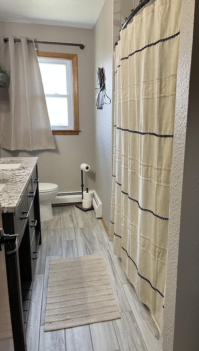 2250 18th Ave, Windom, MN 56101 - bathroom featuring a textured wall, vanity, baseboard heating, and curtained shower