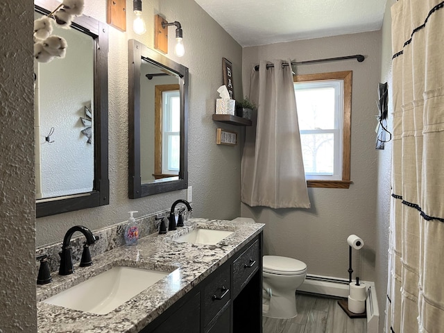 2250 18th Ave, Windom, MN 56101 - full bath with double vanity, wood finished floors, a baseboard radiator, and a textured wall