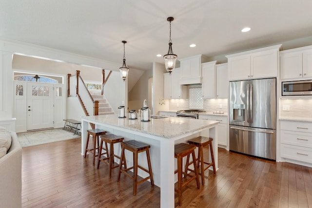 204 8th Ave S, Princeton, MN 55371 - kitchen with stainless steel appliances, a breakfast bar, tasteful backsplash, white cabinetry, and dark wood-style flooring