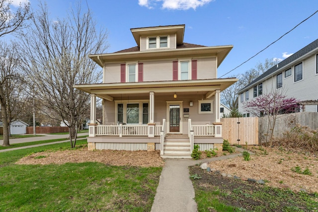 american foursquare style home with covered porch, fence, and a front lawn