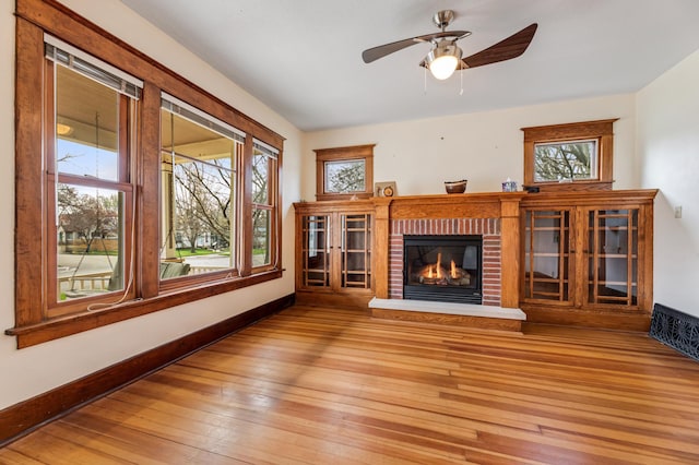 unfurnished living room featuring light wood-style flooring, a brick fireplace, and a wealth of natural light