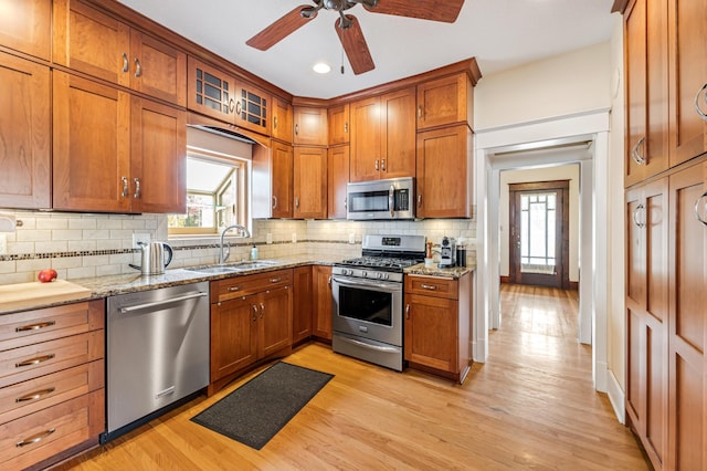 kitchen featuring a sink, stainless steel appliances, brown cabinets, light wood-type flooring, and ceiling fan