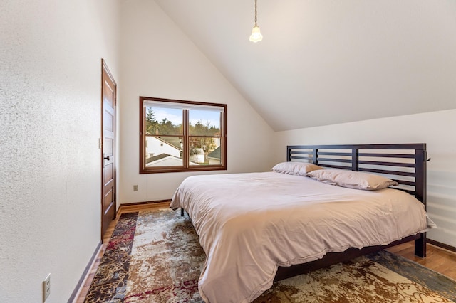 bedroom with baseboards, wood finished floors, and lofted ceiling