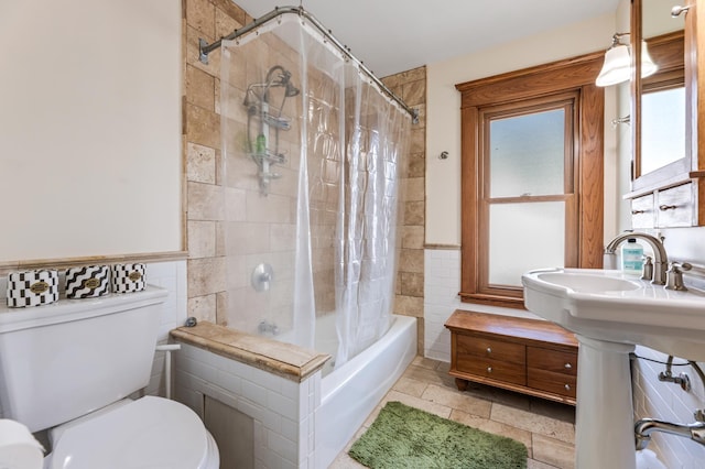 full bath featuring toilet, tile walls, and shower / bathtub combination with curtain