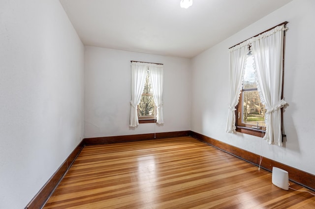 unfurnished room with baseboards and light wood-type flooring