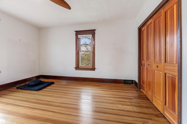 unfurnished bedroom with light wood finished floors, baseboards, a closet, and a ceiling fan