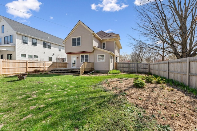 rear view of property featuring a lawn, a wooden deck, and a fenced backyard