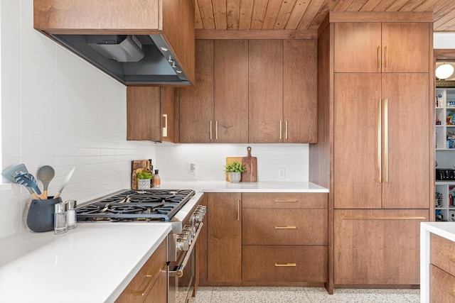 4919 Three Points Blvd, Mound, MN 55364 - kitchen featuring high end stainless steel range oven, dark speckled floor, range hood, decorative backsplash, and light countertops