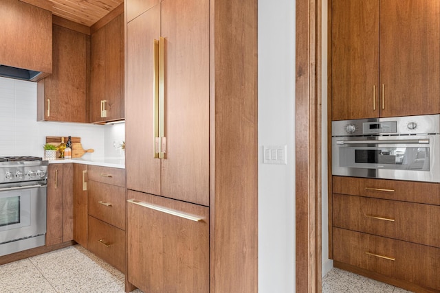 4919 Three Points Blvd, Mound, MN 55364 - kitchen with stainless steel appliances, dark speckled floor, decorative backsplash, and brown cabinets