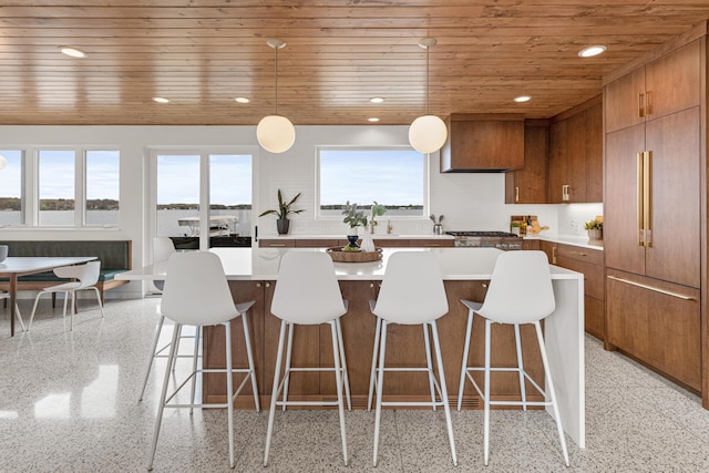 4919 Three Points Blvd, Mound, MN 55364 - kitchen with wooden ceiling, dark speckled floor, brown cabinetry, a kitchen island, and a kitchen breakfast bar